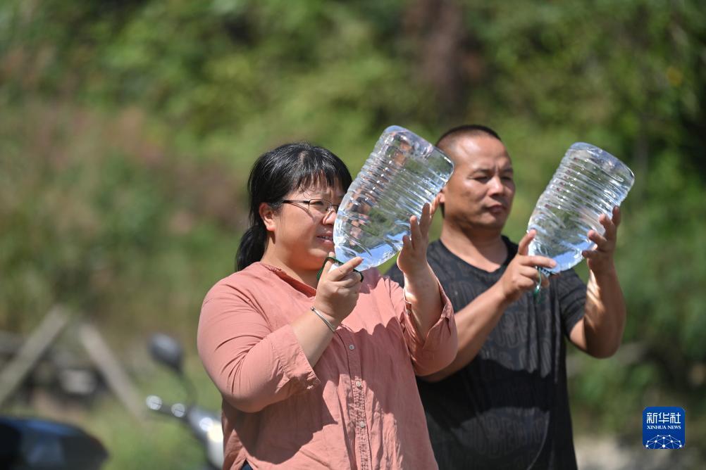 楊寧（左）在查看村民剛剛采集的水樣，為山泉水引水工程做準備（10月8日攝）。新華社記者 黃孝邦 攝